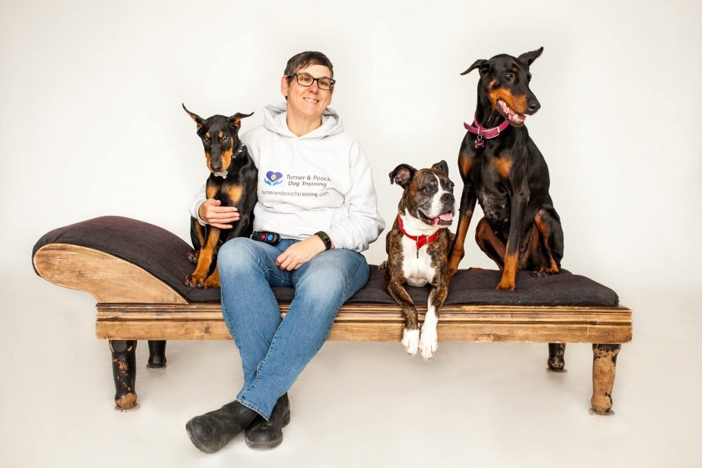 Dog trainer Ineke Turner and three dogs sitting on bench